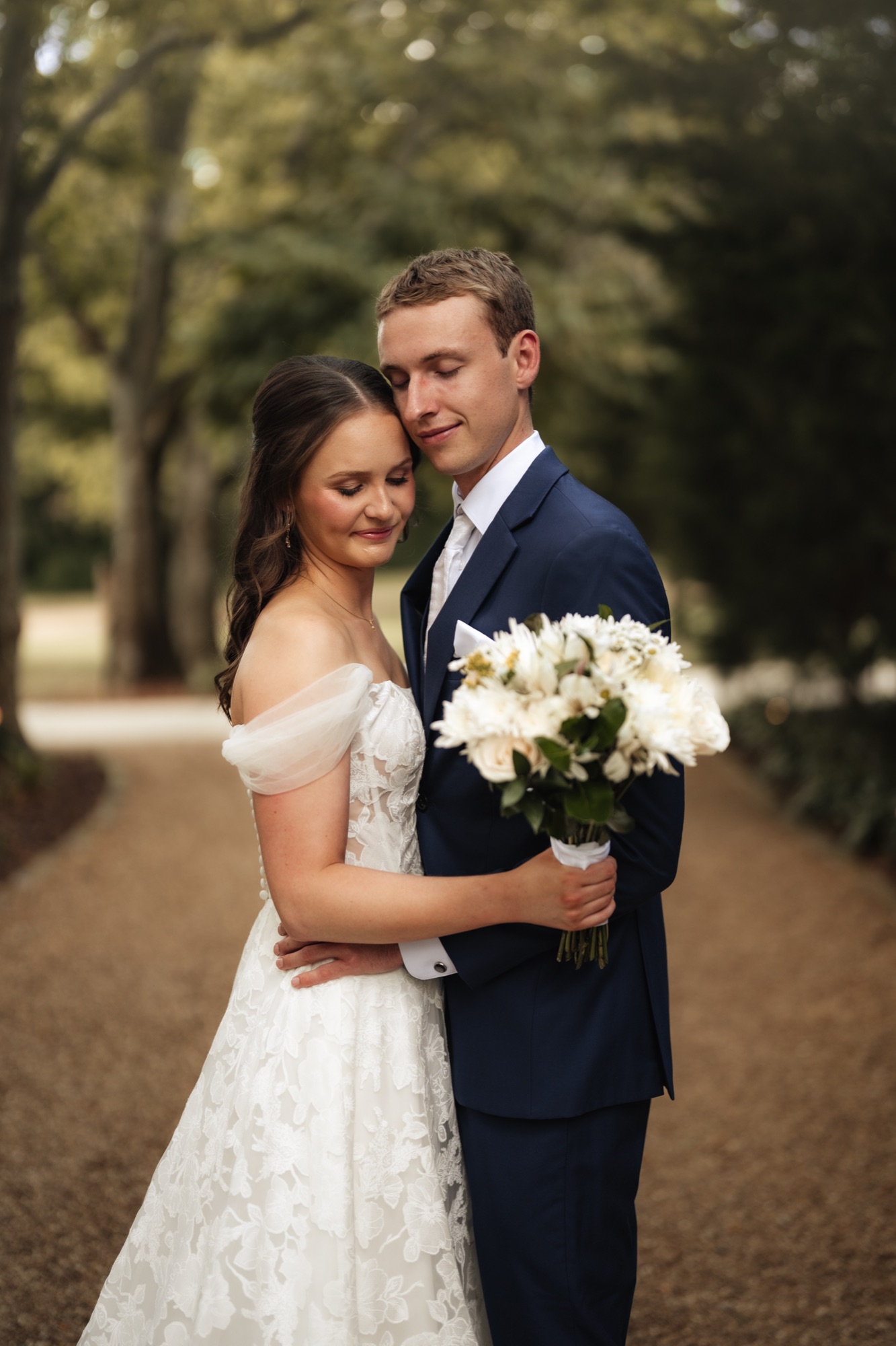 Katie and Zach embrace on a tree-lined path