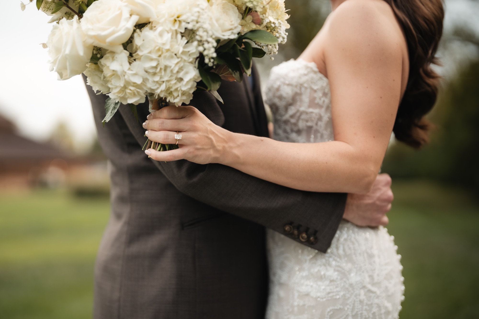 Bride's ring and bouquet detail in an embrace
