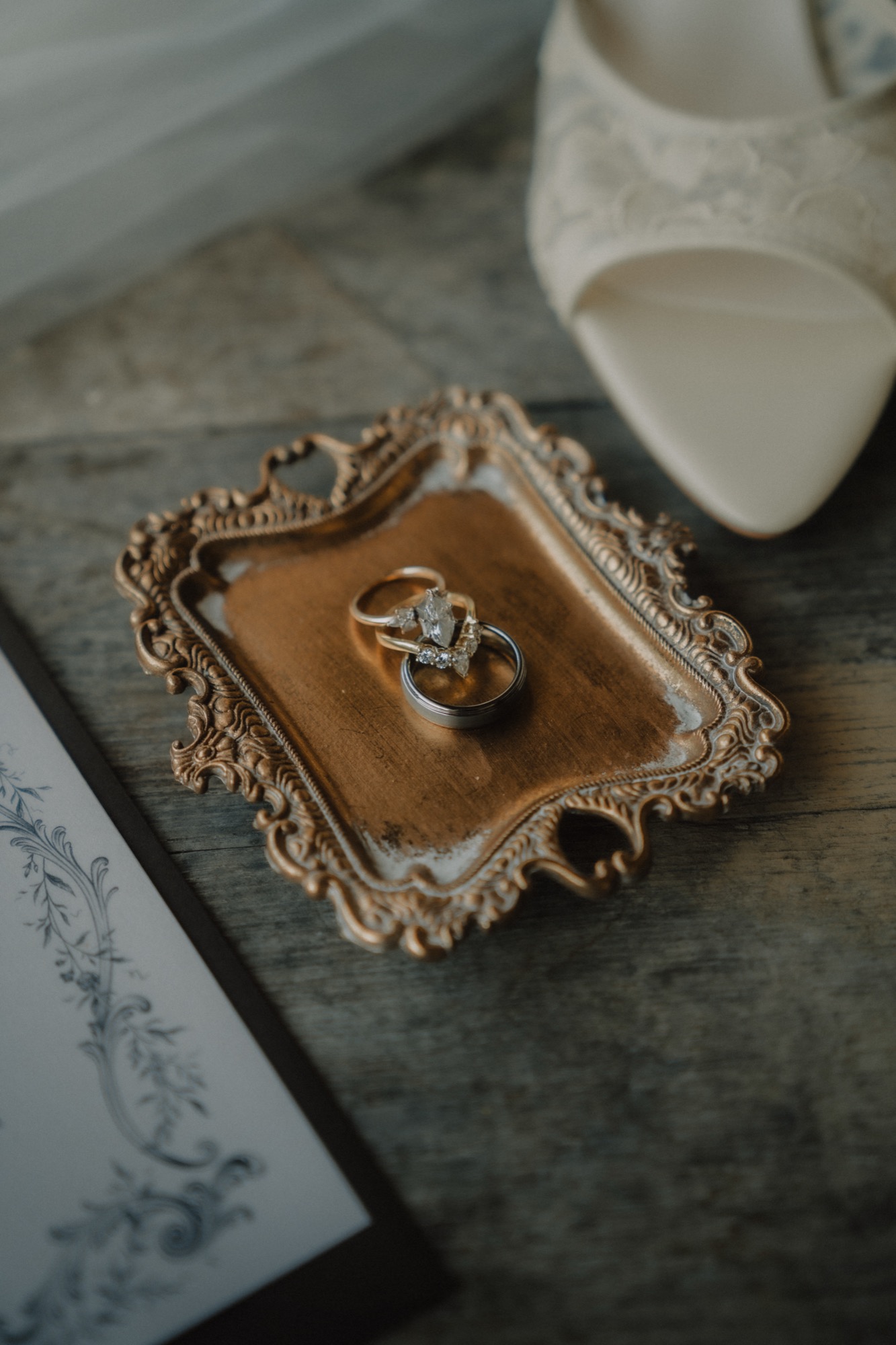 Wedding rings on an antique gilt tray beside the bride's shoes