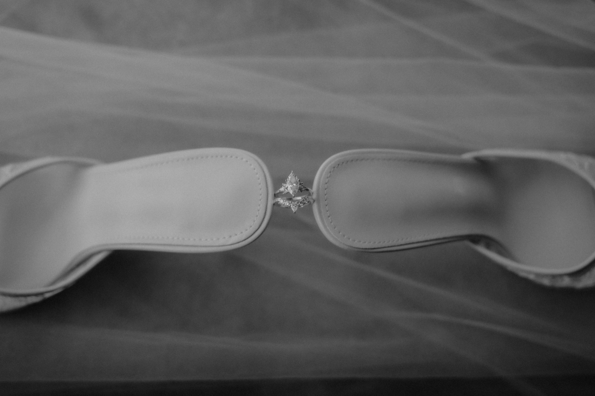 The bride's lace heels laid on her veil with the rings between them