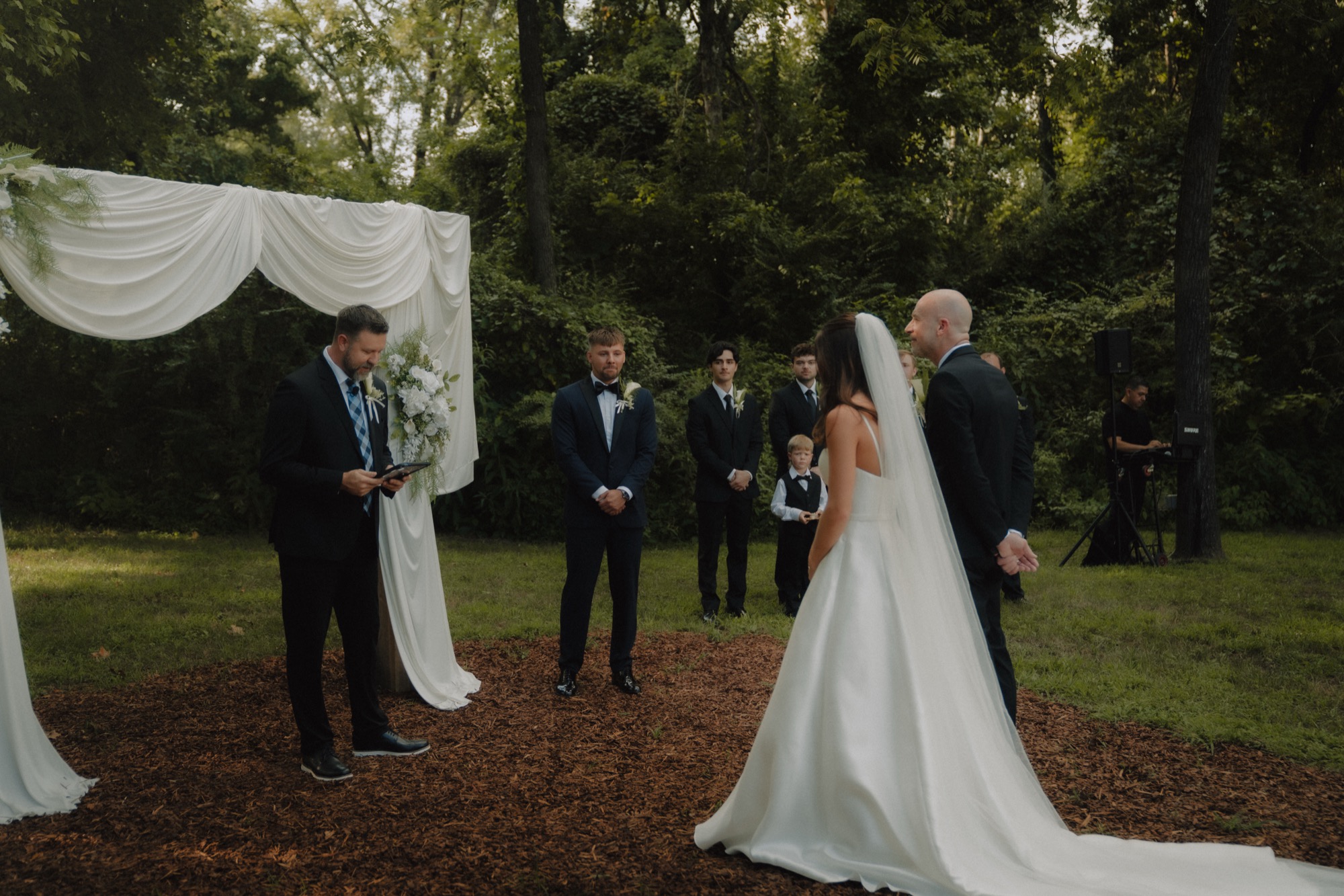 Piper and Zechariah at the draped ceremony arch