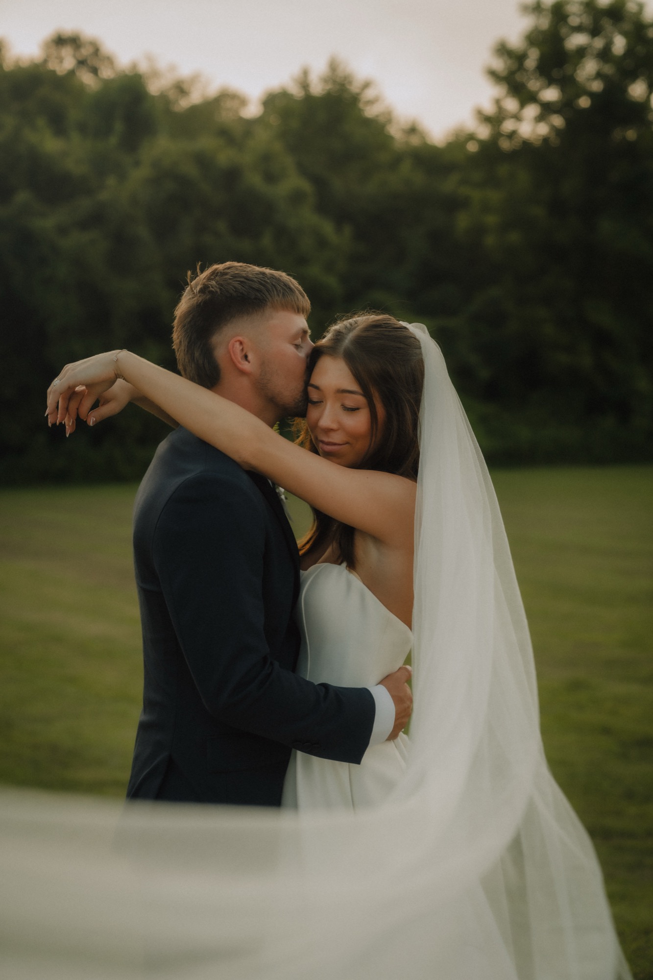 Zechariah kissing Piper's forehead, her veil catching the light