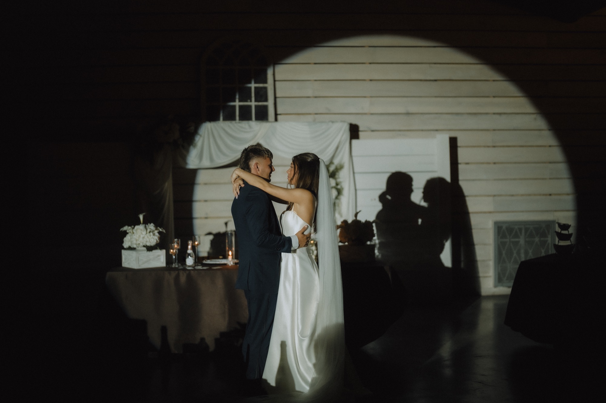 Their first dance, framed through the doorway under string lights